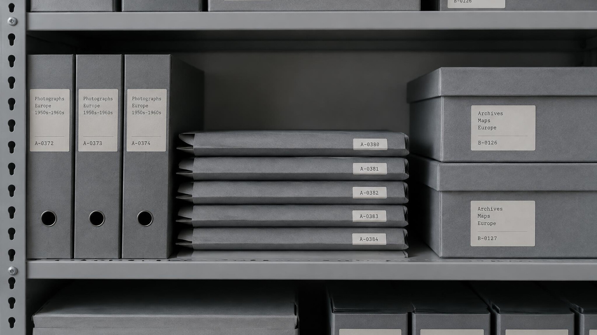 Stack of grey archival folders and boxes with numbered paper labels on a shelf